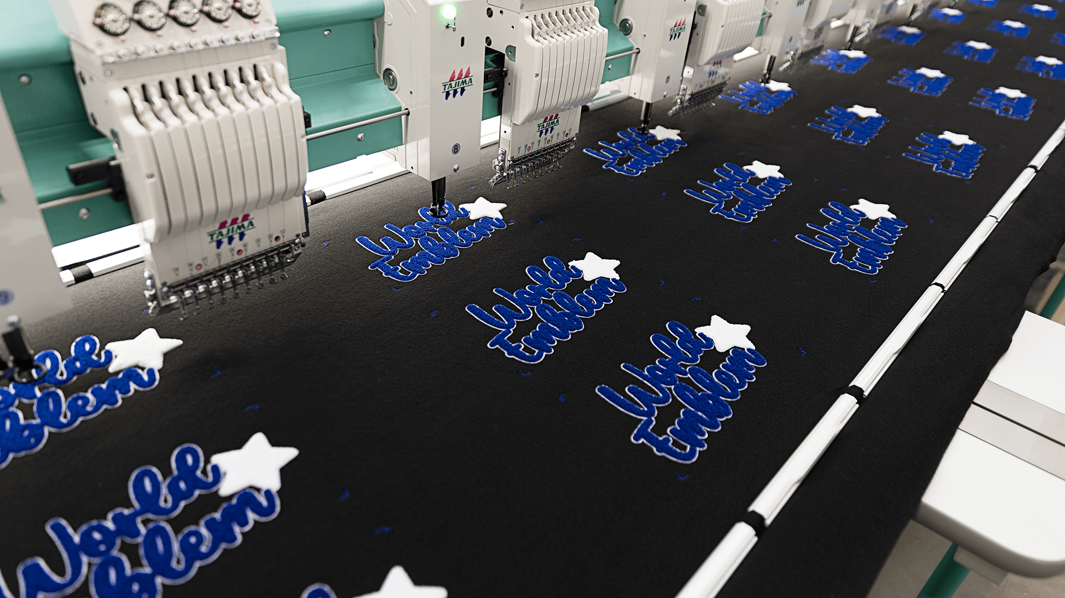 A colorful wall display of FlexStyle emblems featuring various custom designs, logos, and text in vibrant colors and metallic finishes. The emblems include sports themes, brand names, decorative graphics, and dimensional lettering, showcasing premium quality and durability for apparel and promotional branding