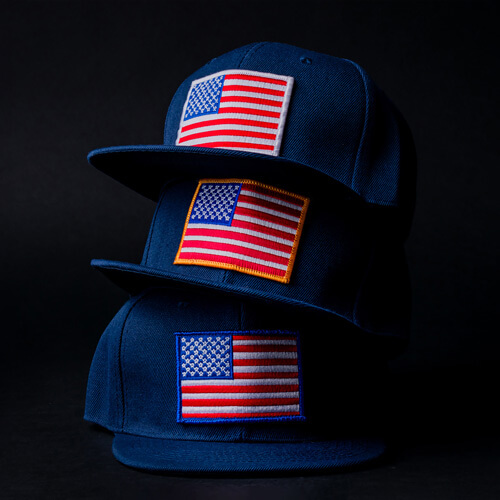 Embroidered American Flag Patches Applied to Three Stacked Navy Blue Baseball Caps
