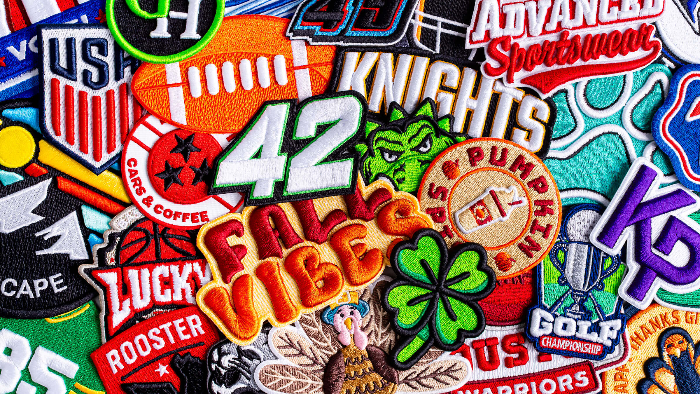 A variety of 3D Embroidered patches layered flat on top of one another, covering the surface