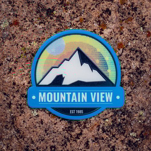 FlexStyle Holographic Mountain View emblem laid flat on a cork board